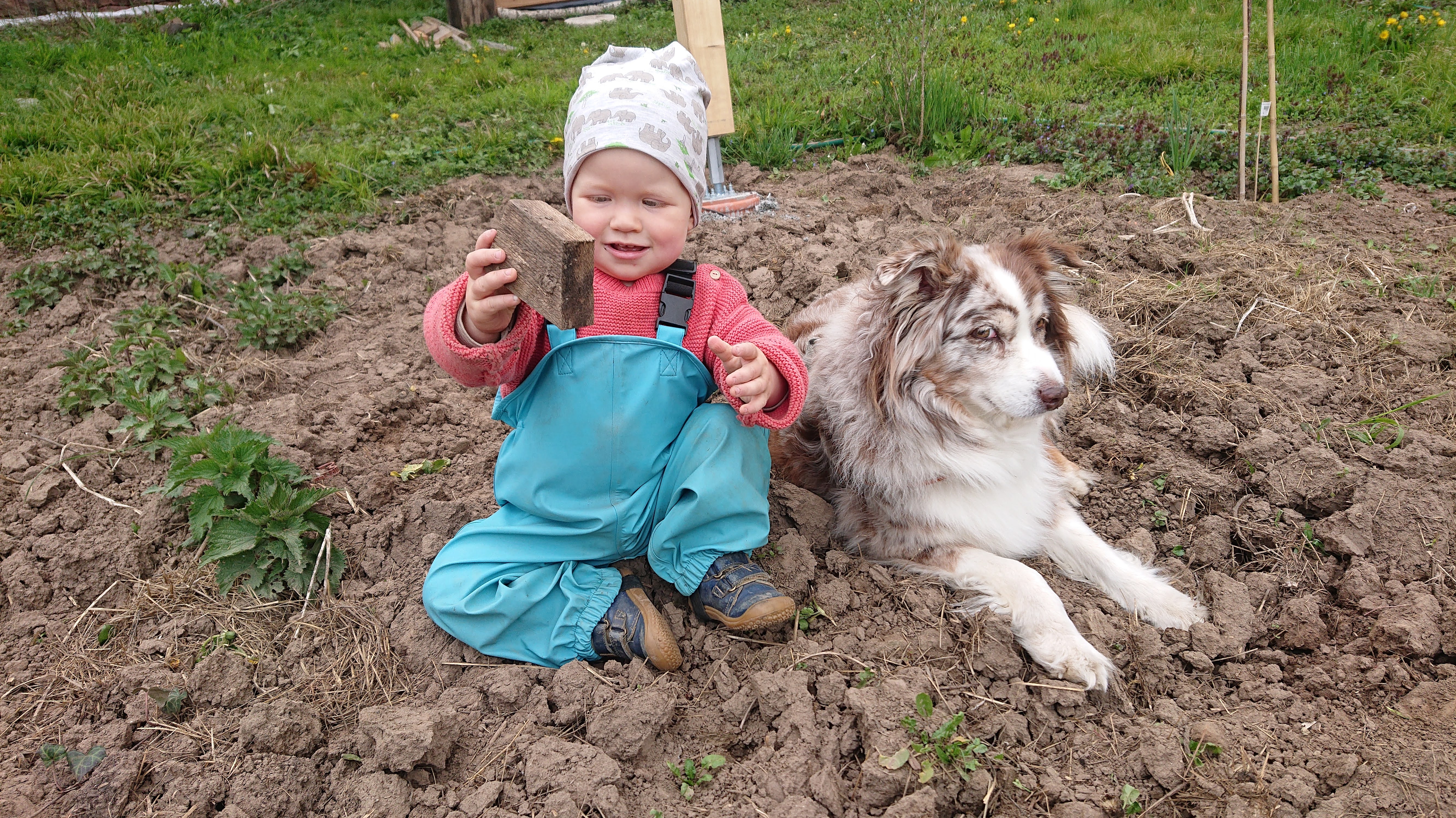 Amy sitzt mit einem kleinen Kind im Garten